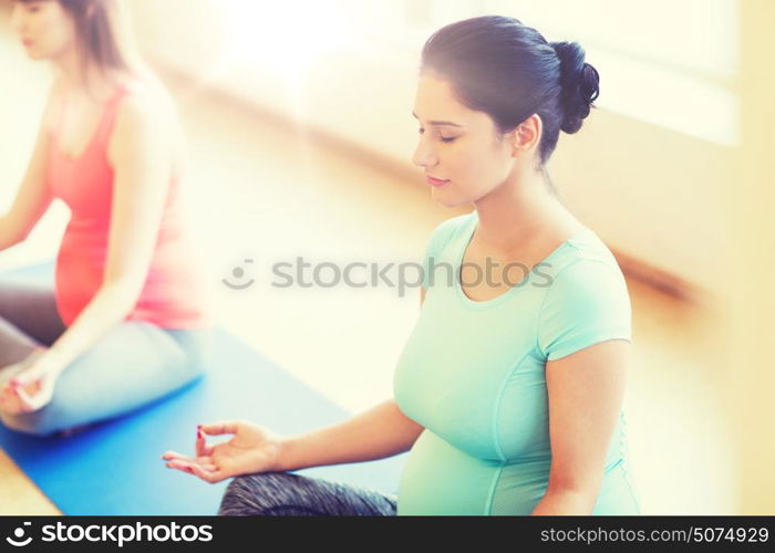 pregnancy, sport, fitness, people and healthy lifestyle concept - group of happy pregnant women exercising yoga and meditating in lotus pose in gym. happy pregnant women exercising yoga in gym
