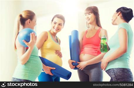 pregnancy, sport, fitness, people and healthy lifestyle concept - group of happy pregnant women with sports equipment talking in gym. group of happy pregnant women talking in gym