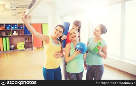 pregnancy, sport, fitness, people and healthy lifestyle concept - group of happy pregnant women with sports stuff taking selfie by smartphone in gym. pregnant women taking selfie by smartphone in gym. pregnant women taking selfie by smartphone in gym