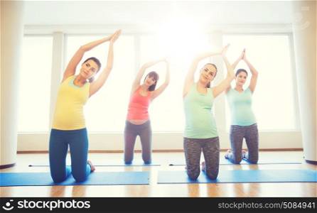 pregnancy, sport, fitness, people and healthy lifestyle concept - group of happy pregnant women exercising on mats in gym. happy pregnant women exercising on mats in gym. happy pregnant women exercising on mats in gym