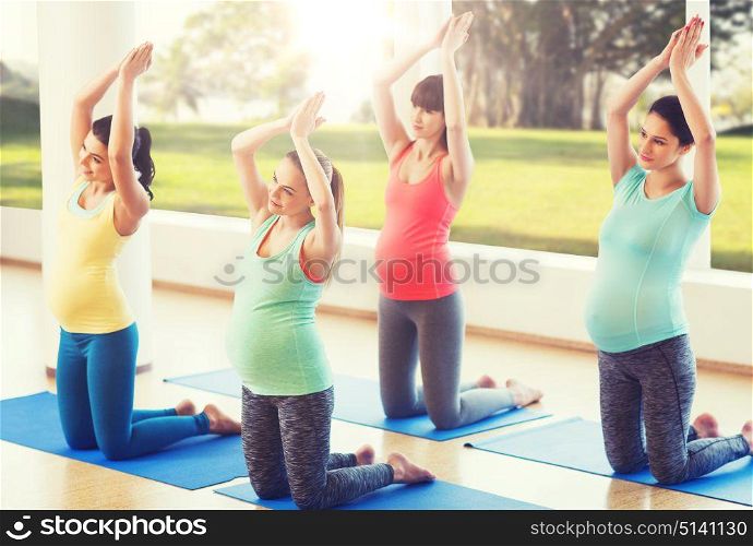 pregnancy, sport, fitness, people and healthy lifestyle concept - group of happy pregnant women exercising on mats in gym. happy pregnant women exercising on mats in gym