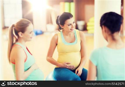 pregnancy, sport, fitness, people and healthy lifestyle concept - group of happy pregnant women sitting and talking on balls in gym. happy pregnant women sitting on balls in gym
