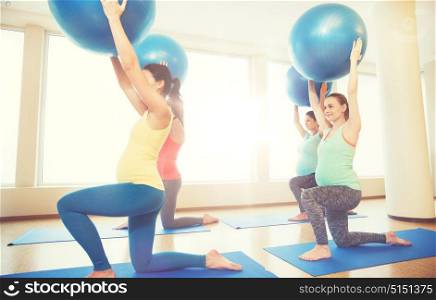 pregnancy, sport, fitness, people and healthy lifestyle concept - group of happy pregnant women exercising with ball in gym. happy pregnant women exercising with ball in gym
