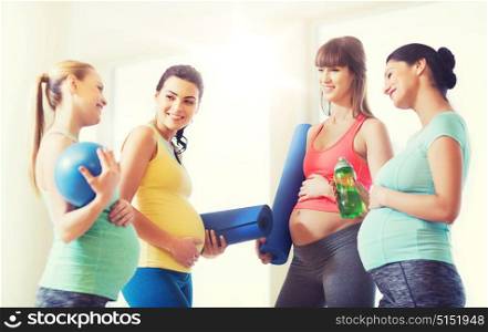 pregnancy, sport, fitness, people and healthy lifestyle concept - group of happy pregnant women with sports equipment talking in gym. group of happy pregnant women talking in gym