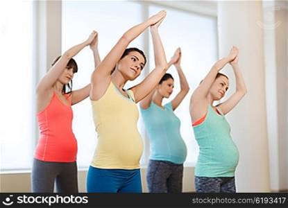 pregnancy, sport, fitness, people and healthy lifestyle concept - group of happy pregnant women exercising in gym