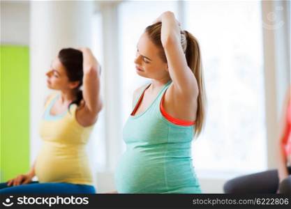 pregnancy, sport, fitness, people and healthy lifestyle concept - group of happy pregnant women exercising in gym