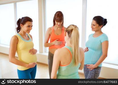 pregnancy, sport, fitness, people and healthy lifestyle concept - group of happy pregnant women talking in gym. happy pregnant women talking in gym. happy pregnant women talking in gym