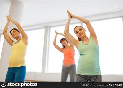 pregnancy, sport, fitness, people and healthy lifestyle concept - group of happy pregnant women exercising on mats in gym. happy pregnant women exercising on mats in gym. happy pregnant women exercising on mats in gym