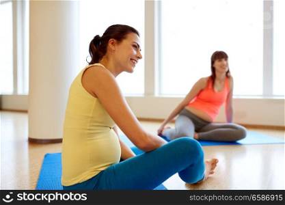 pregnancy, sport, fitness, people and healthy lifestyle concept - group of happy pregnant women sitting and talking on mats in gym. happy pregnant women sitting on mats in gym