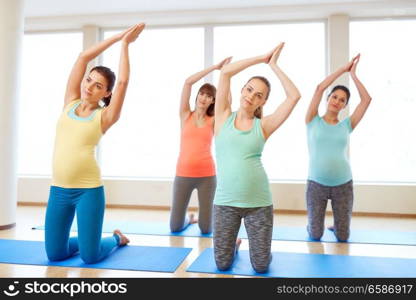 pregnancy, sport, fitness, people and healthy lifestyle concept - group of happy pregnant women exercising on mats in gym. happy pregnant women exercising on mats in gym
