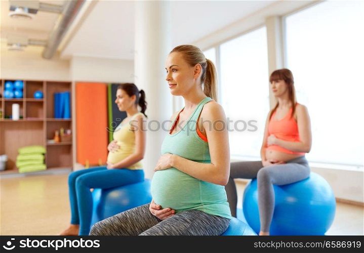 pregnancy, sport, fitness, people and healthy lifestyle concept - group of happy pregnant women sitting on exercise balls in gym. pregnant women sitting on exercise balls in gym