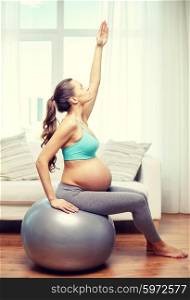 pregnancy, sport, fitness, people and healthy lifestyle concept - happy pregnant woman exercising on fitball at home