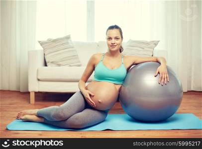 pregnancy, sport, fitness, people and healthy lifestyle concept - happy pregnant woman exercising with fitball at home