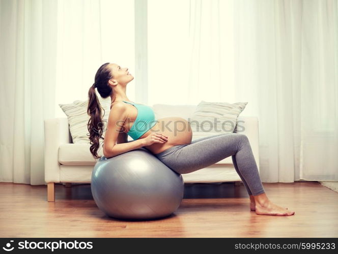 pregnancy, sport, fitness, people and healthy lifestyle concept - happy pregnant woman exercising on fitball at home