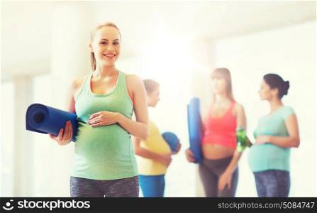 pregnancy, sport, fitness, people and healthy lifestyle concept - happy pregnant woman with mat in gym. happy pregnant woman with mat in gym. happy pregnant woman with mat in gym