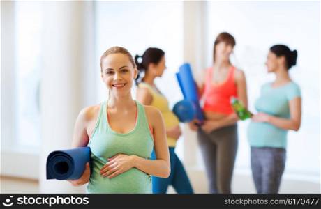 pregnancy, sport, fitness, people and healthy lifestyle concept - happy pregnant woman with mat in gym