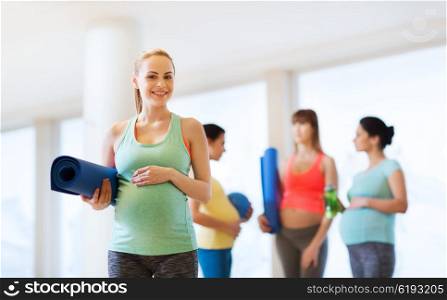 pregnancy, sport, fitness, people and healthy lifestyle concept - happy pregnant woman with mat in gym