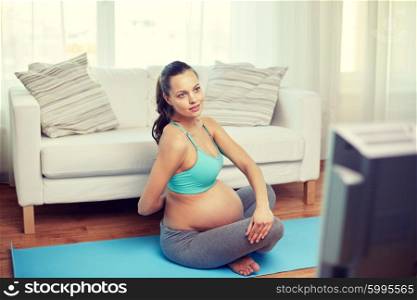 pregnancy, sport, people and healthy lifestyle concept - happy pregnant woman exercising and watching tv at home