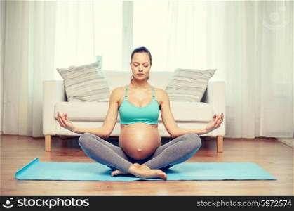 pregnancy, sport, yoga, people and healthy lifestyle concept - happy pregnant woman meditating at home