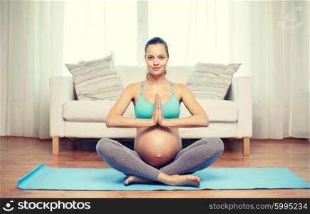 pregnancy, sport, yoga, people and healthy lifestyle concept - happy pregnant woman meditating at home