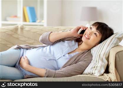 pregnancy, technology and people concept - happy pregnant asian woman calling on smartphone at home. happy pregnant woman calling on smartphone at home