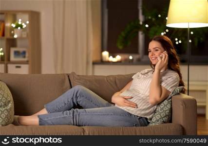 pregnancy, technology and people concept - happy pregnant woman calling on smartphone at home. happy pregnant woman calling on smartphone at home