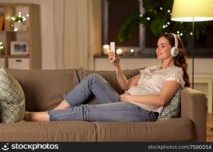 pregnancy, technology and people concept - happy pregnant woman with smartphone and headphones listening to music at home. pregnant woman with smartphone and headphones
