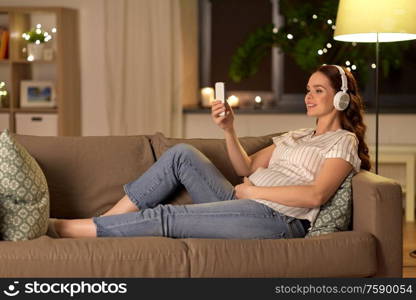 pregnancy, technology and people concept - happy pregnant woman with smartphone and headphones listening to music at home. pregnant woman with smartphone and headphones