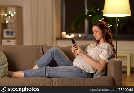 pregnancy, technology and people concept - happy pregnant woman with smartphone at home. happy pregnant woman with smartphone at home