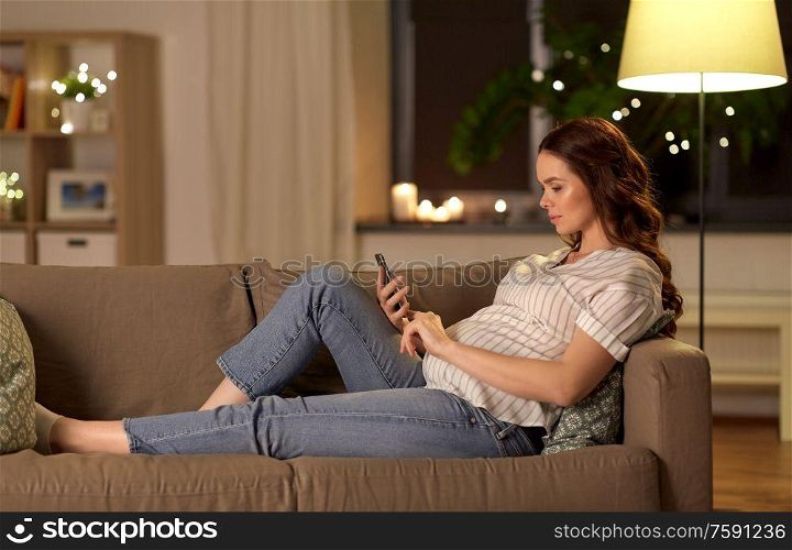 pregnancy, technology and people concept - happy pregnant woman with smartphone at home. happy pregnant woman with smartphone at home