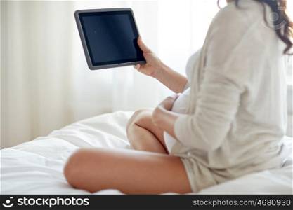 pregnancy, technology, people and expectation concept - close up of pregnant woman with tablet pc computer in bed at home