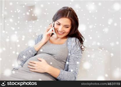 pregnancy, technology, people, winter and expectation concept - happy pregnant woman calling on smartphone at home over snow