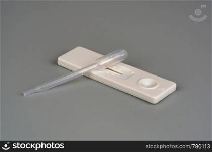 Pregnancy test stick with a pipette on a gray background