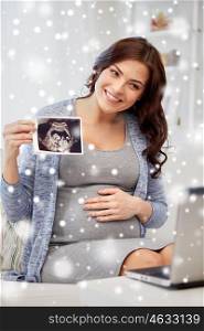 pregnancy, winter, christmas and people concept - happy pregnant woman with laptop computer having video call and showing ultrasound image at home over snow