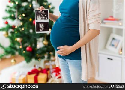 pregnancy, winter holidays and people concept - close up of pregnant woman with baby ultrasound images at christmas. pregnant woman with ultrasound images at christmas