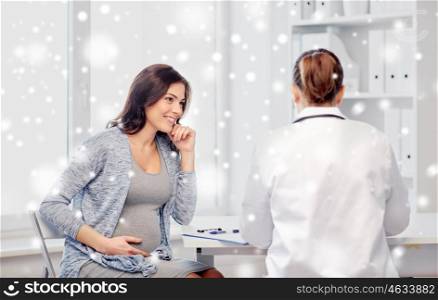 pregnancy, winter, medicine, healthcare and people concept - gynecologist doctor with clipboard and pregnant woman meeting at hospital over snow