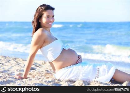 Pregnannt mother woman with baby shoes on belly at the beach