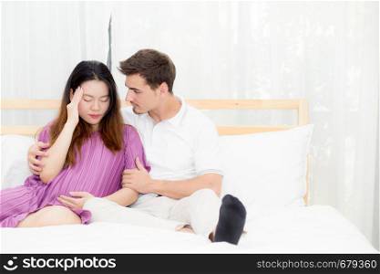 Pregnant asian woman belly acheand feel sick and husband with take care on bedroom, family relationship concept.