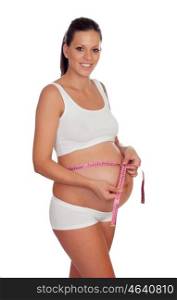 Pregnant brunette woman measuring her belly isolated on a white background