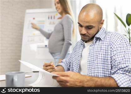 pregnant businesswoman giving presentation office while coworker takes notes