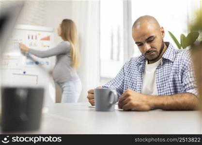 pregnant businesswoman giving presentation while male coworker listens
