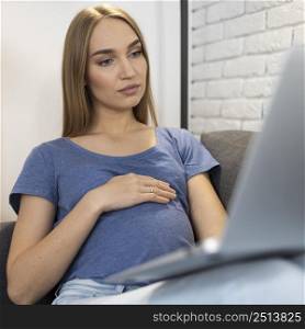 pregnant businesswoman sitting couch working laptop