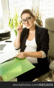 Pregnant businesswoman sitting in chair an working with papers