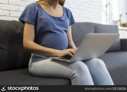pregnant businesswoman sitting sofa working laptop
