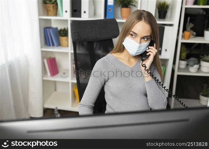pregnant businesswoman talking phone while wearing medical mask