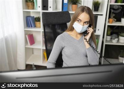 pregnant businesswoman talking phone while wearing medical mask