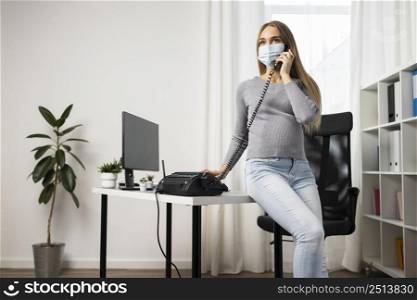 pregnant businesswoman with medical mask talking phone