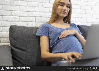 pregnant businesswoman working laptop from couch