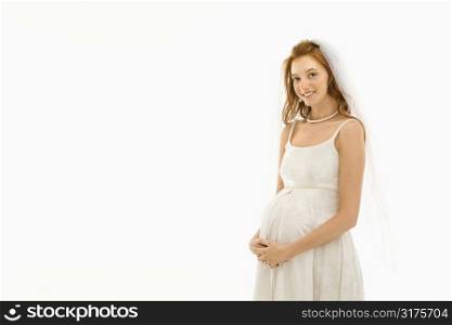 Pregnant Caucasian bride with hands on her belly.