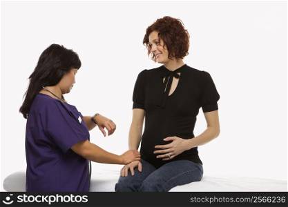 Pregnant Caucasian mid-adult woman having vital signs checked by nurse.